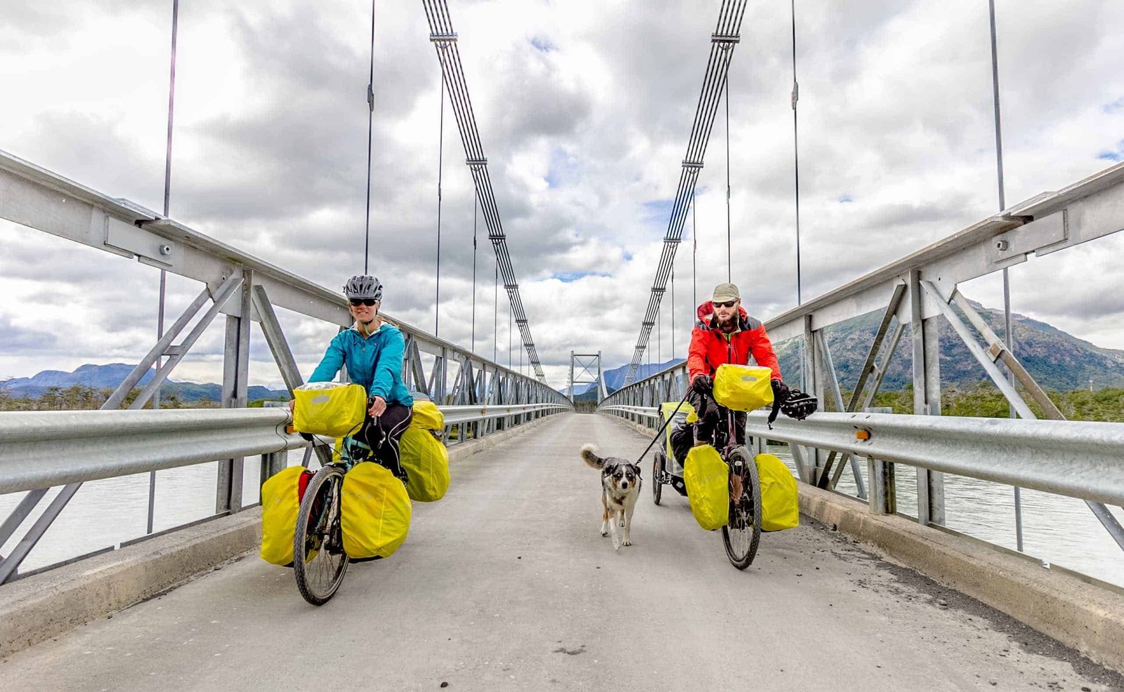 Two people on bicycles with a dog walking between them